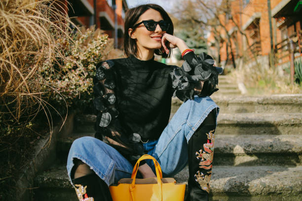 Woman in trendy outfit with statement sleeves, embroidered boots, and yellow handbag, embodying fashionable accessories.